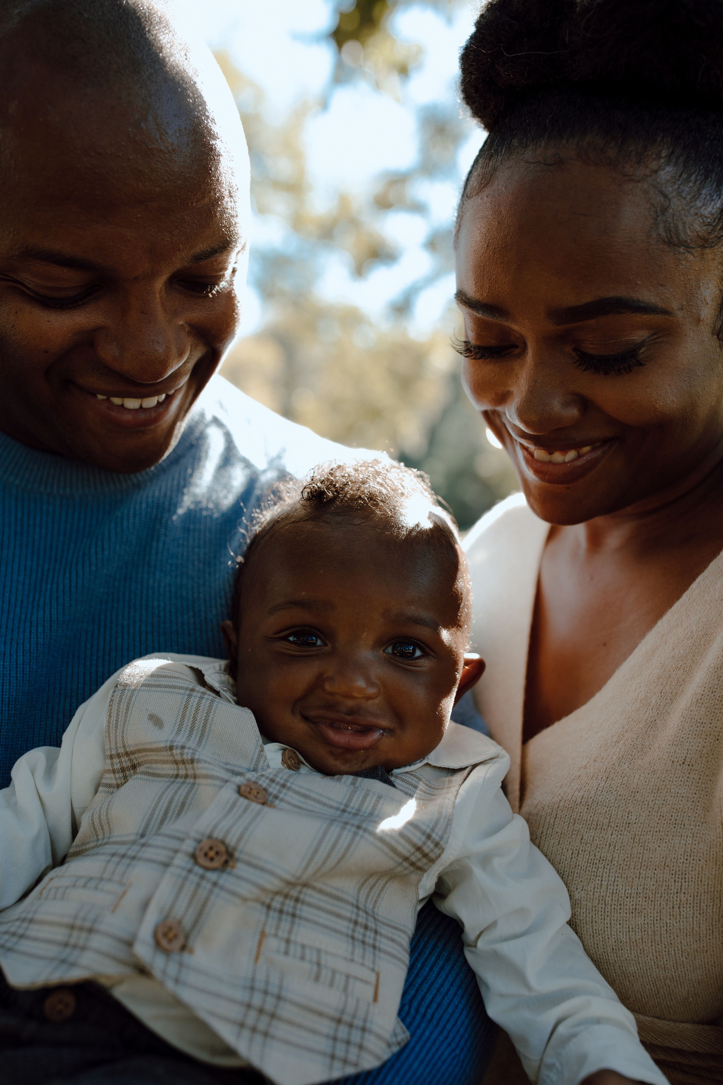 Loving family moment captured in warm sunlight as they smile together.