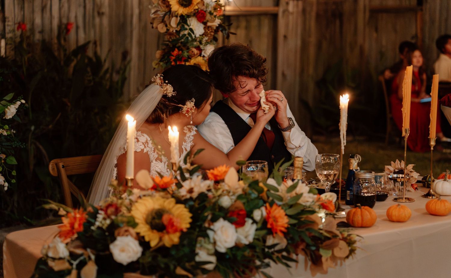 Candlelit autumn wedding table with pumpkins and floral centerpieces.