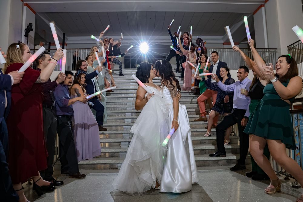 Wedding celebration with guests forming a tunnel of raised arms as newlyweds exit.