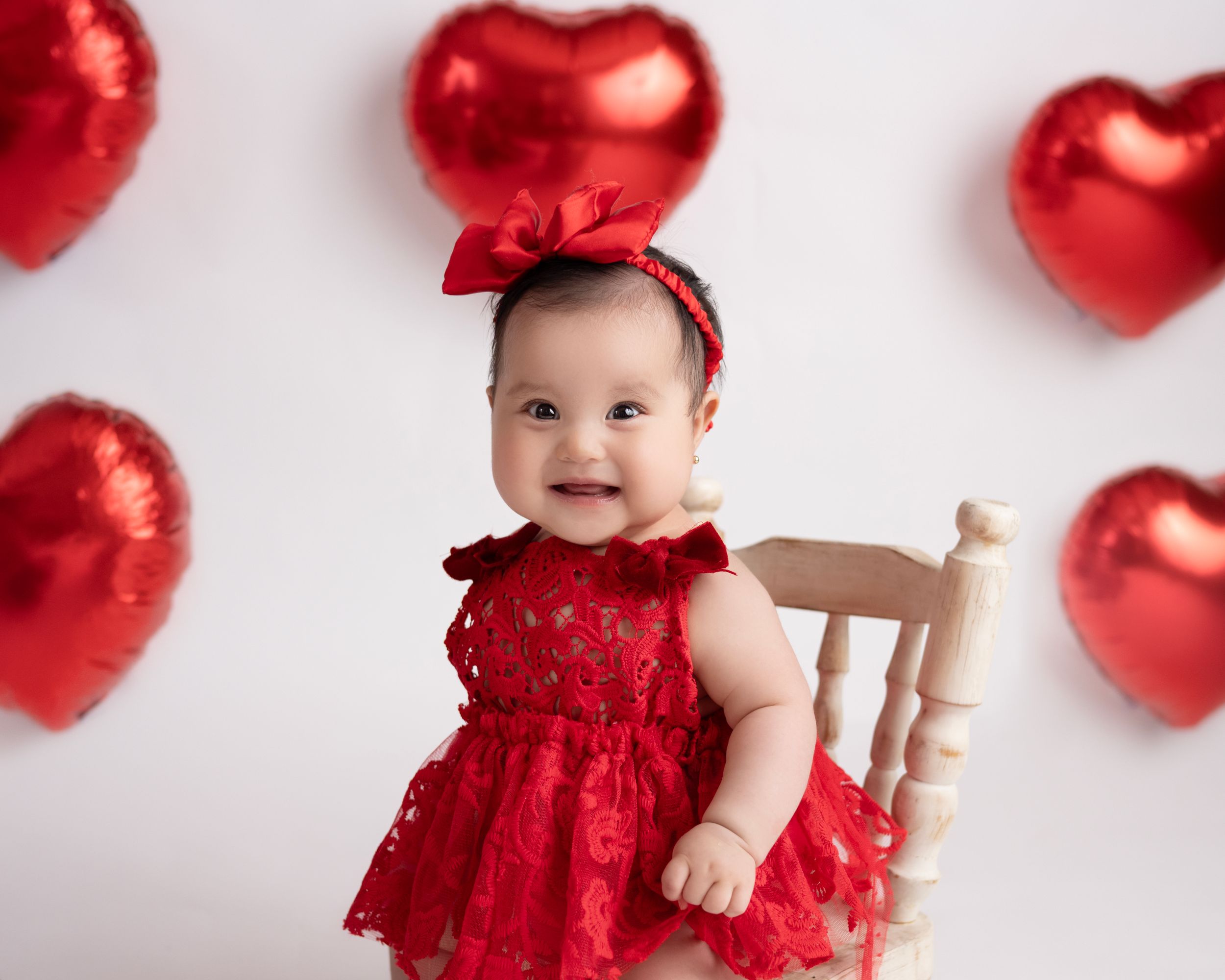 Valentine's themed baby photo with red hearts and ruffled red dress.