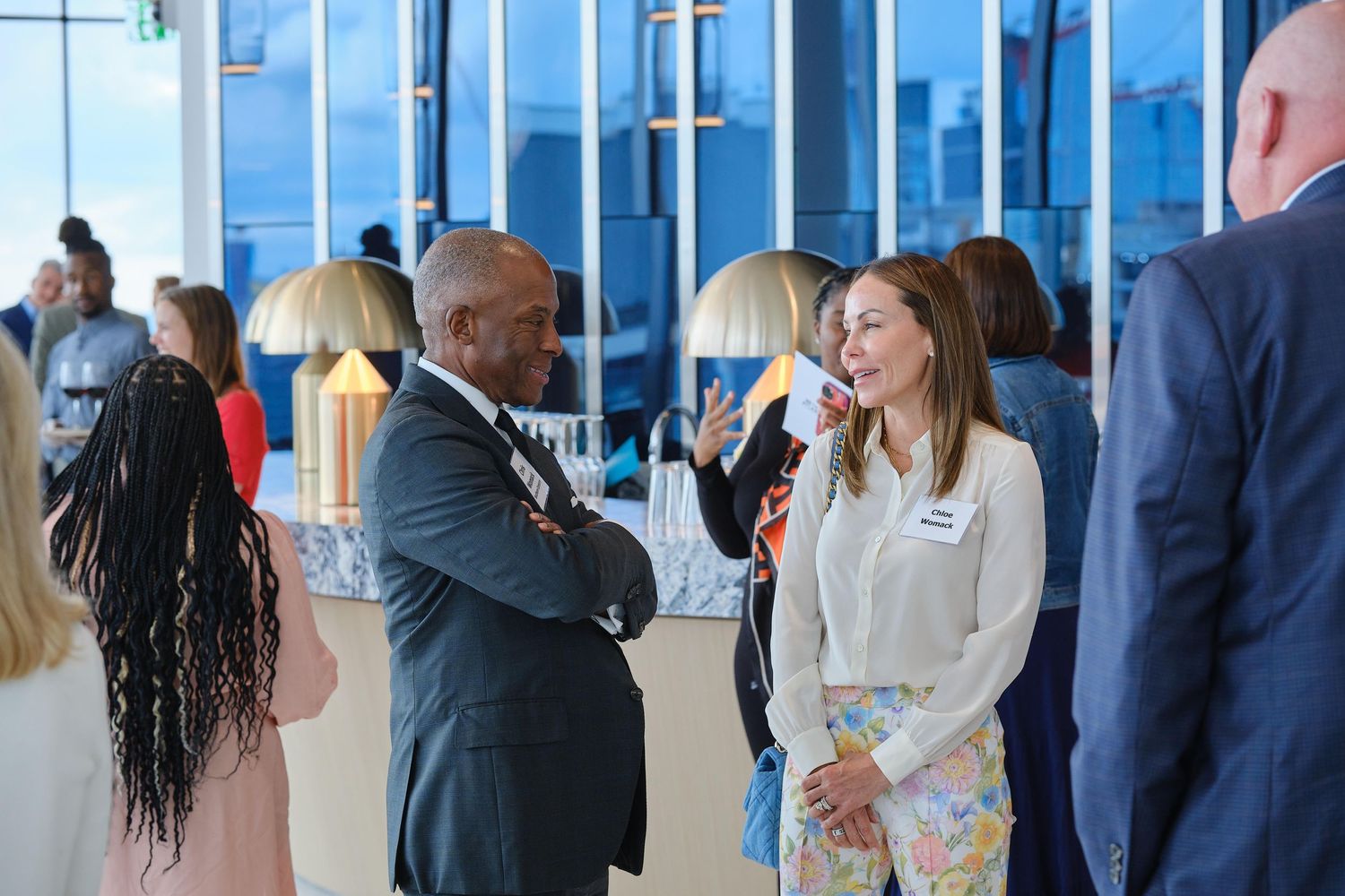 Professional networking event with attendees mingling in a modern high-rise space.