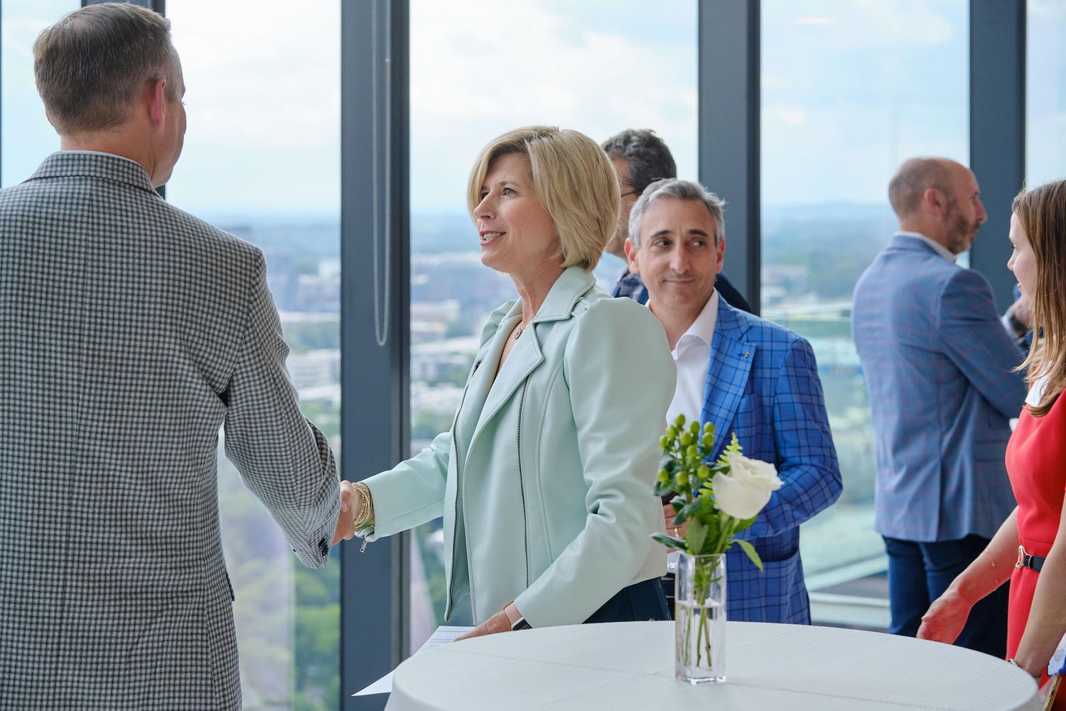 Business professionals networking at an elegant reception with city views.