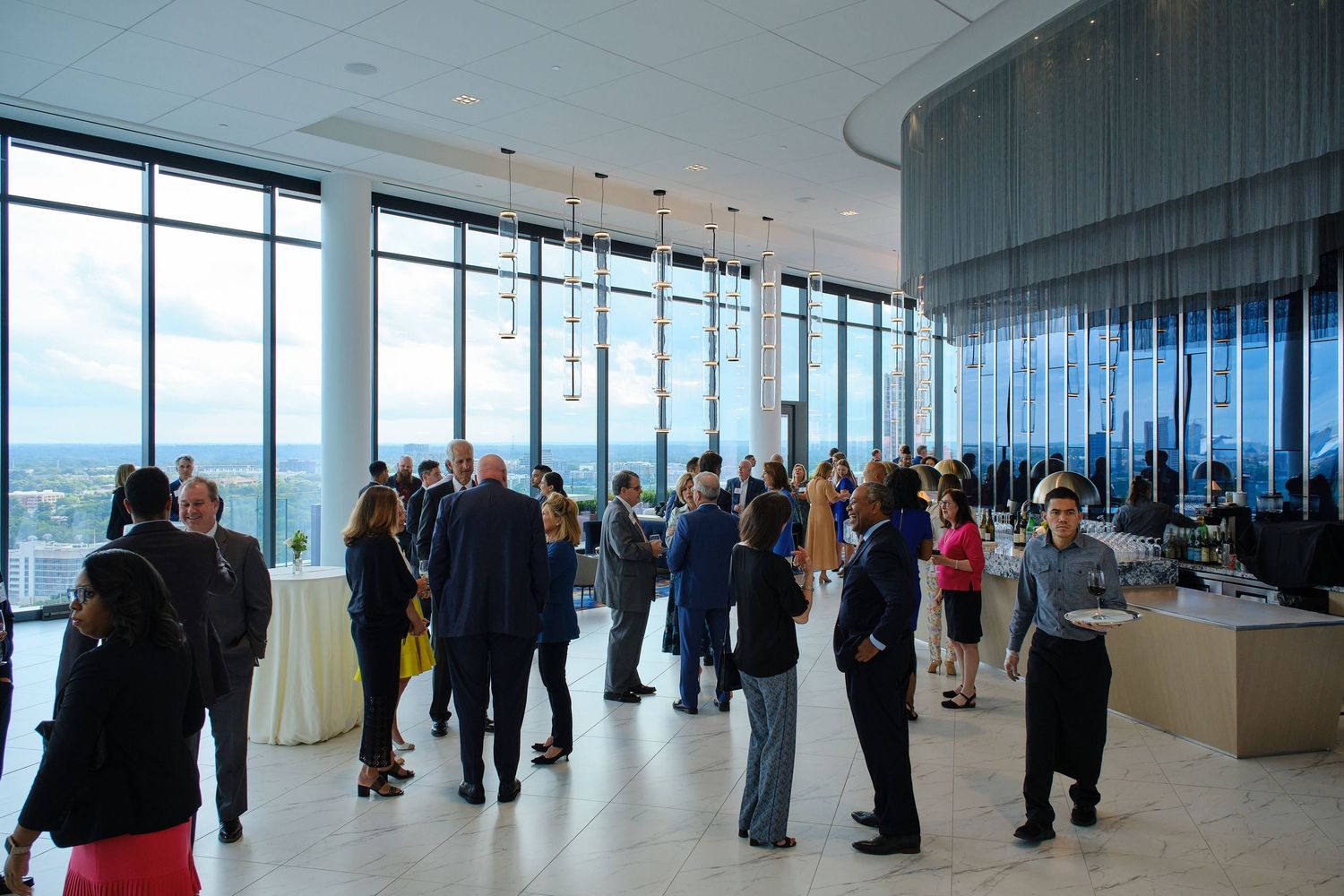 Corporate gathering in a modern high-rise space with panoramic windows and elegant lighting fixtures.