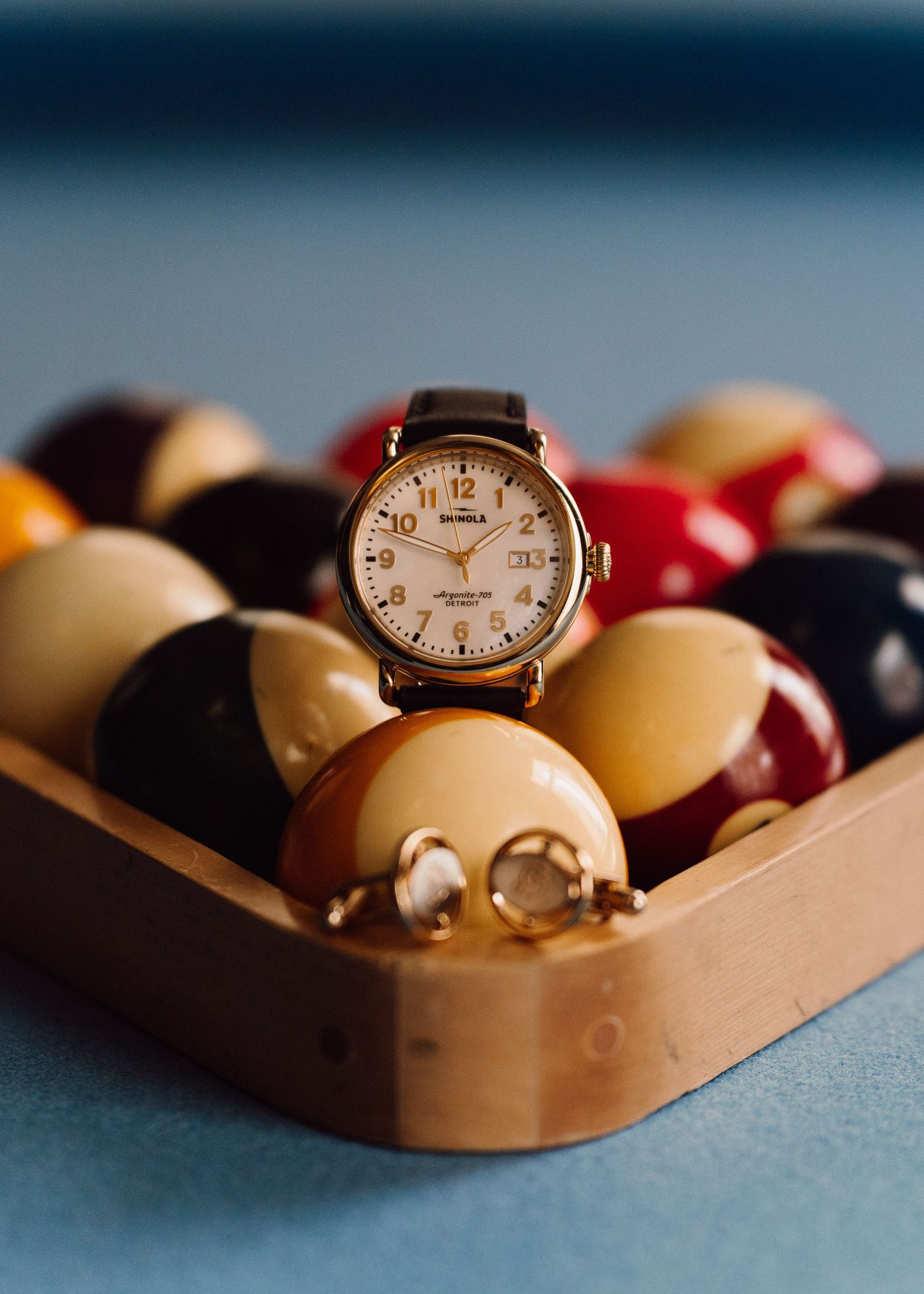 Vintage watch and cufflinks artistically arranged in a wooden tray with blurred background.