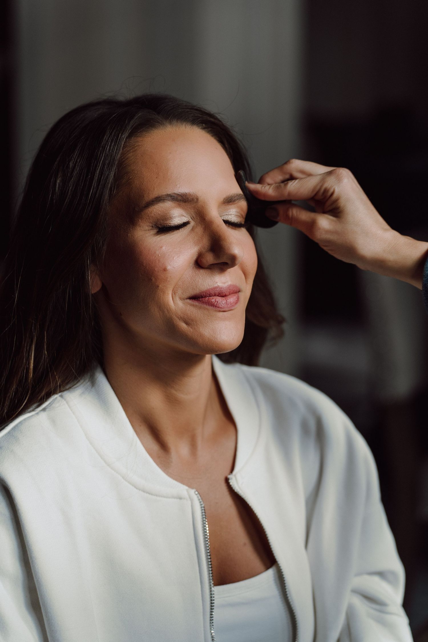 Close-up of makeup being applied to someone wearing a white robe.