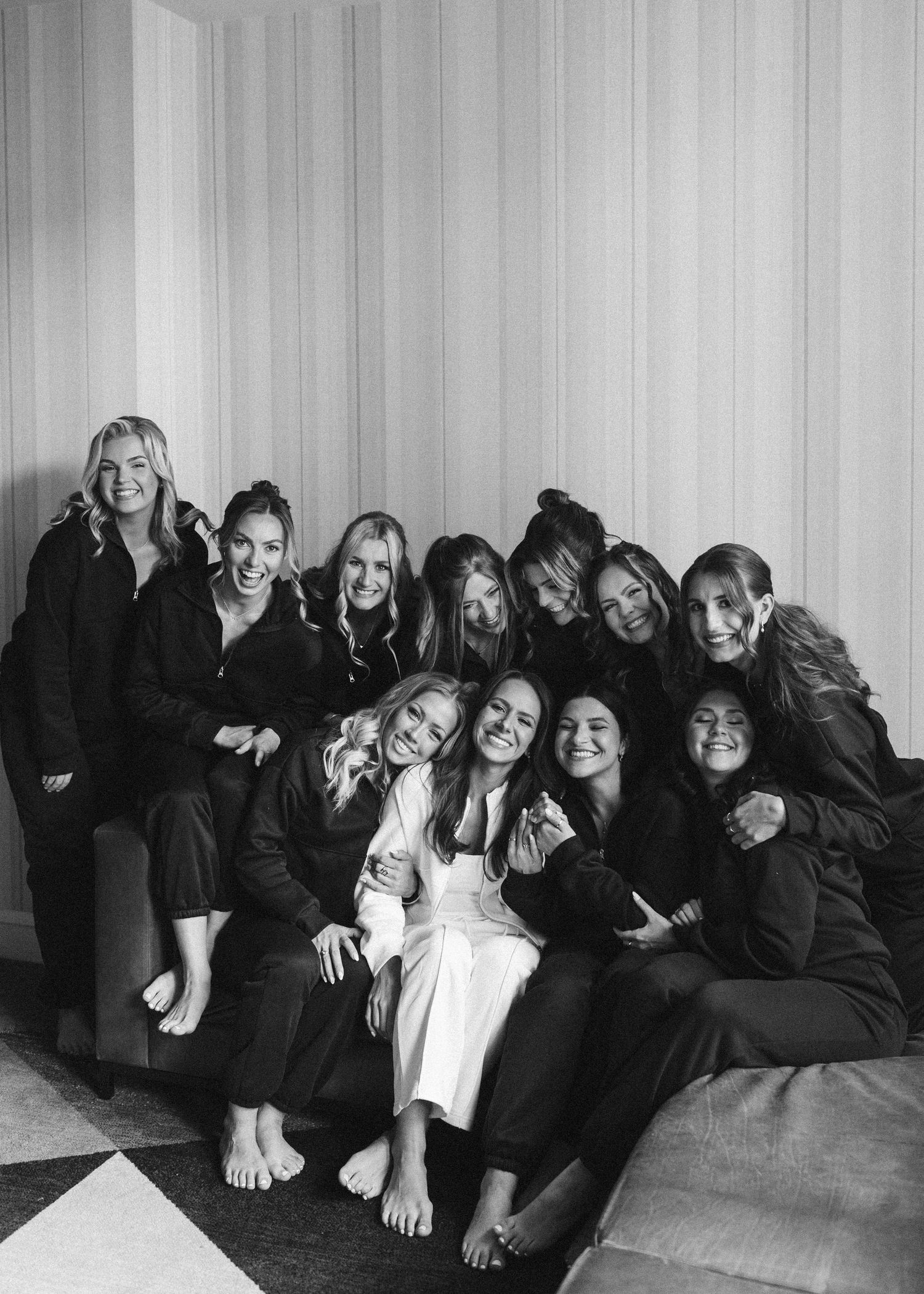 Black and white candid photo of bridal party lounging together and laughing.