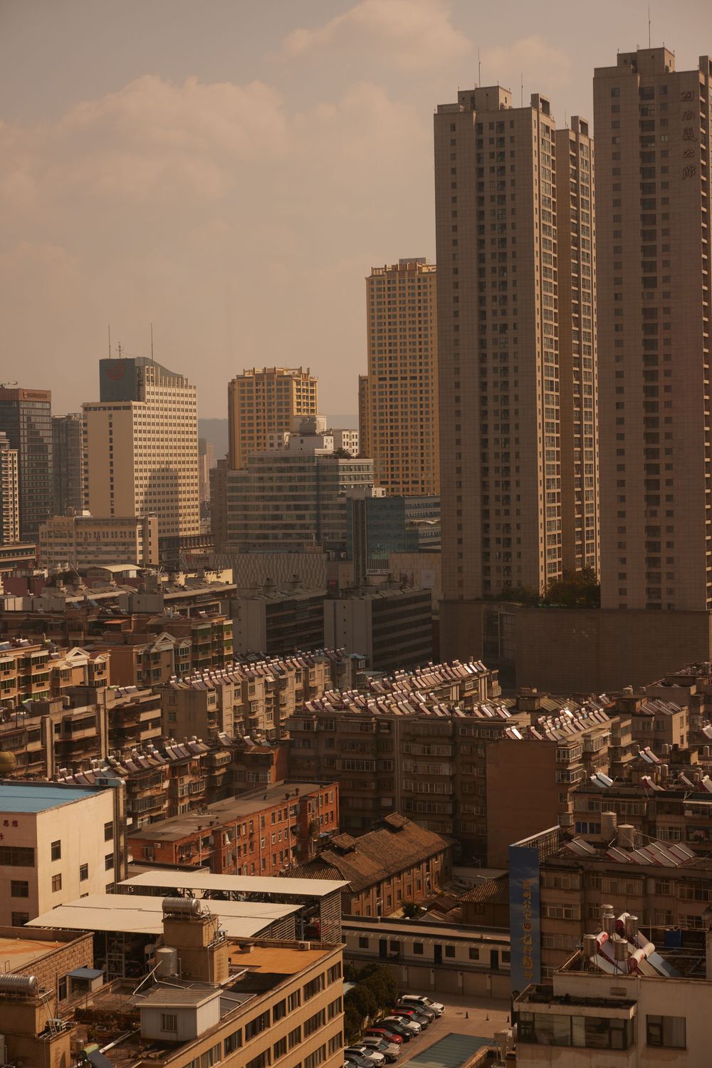 Urban cityscape with tall residential towers and apartment buildings under a hazy golden sky in Shanghai.