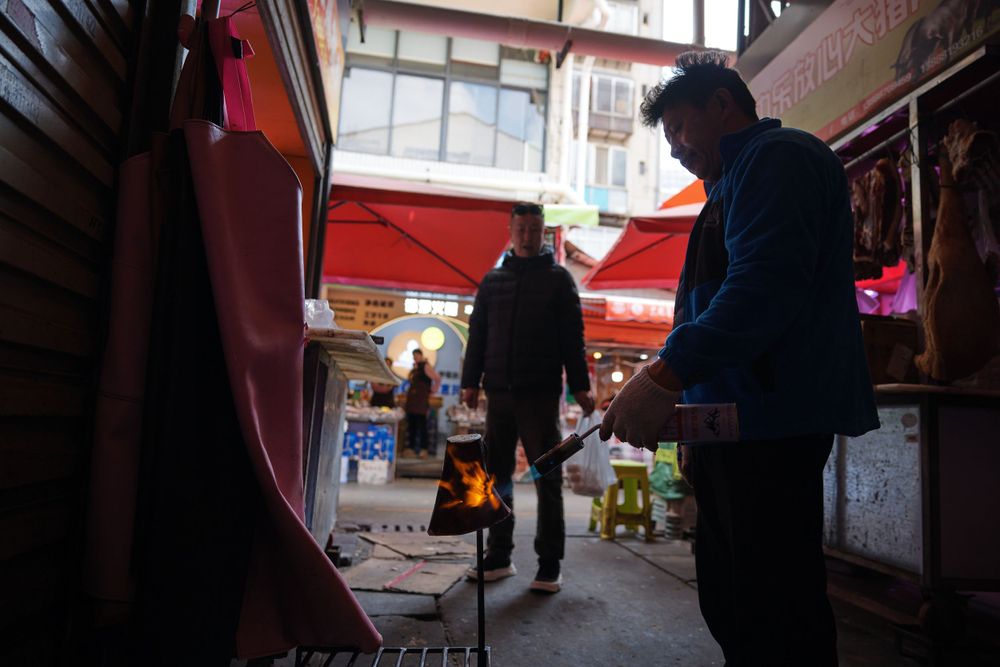 Silhouetted figures browse through an indoor market or bazaar with warm lighting and narrow walkways.