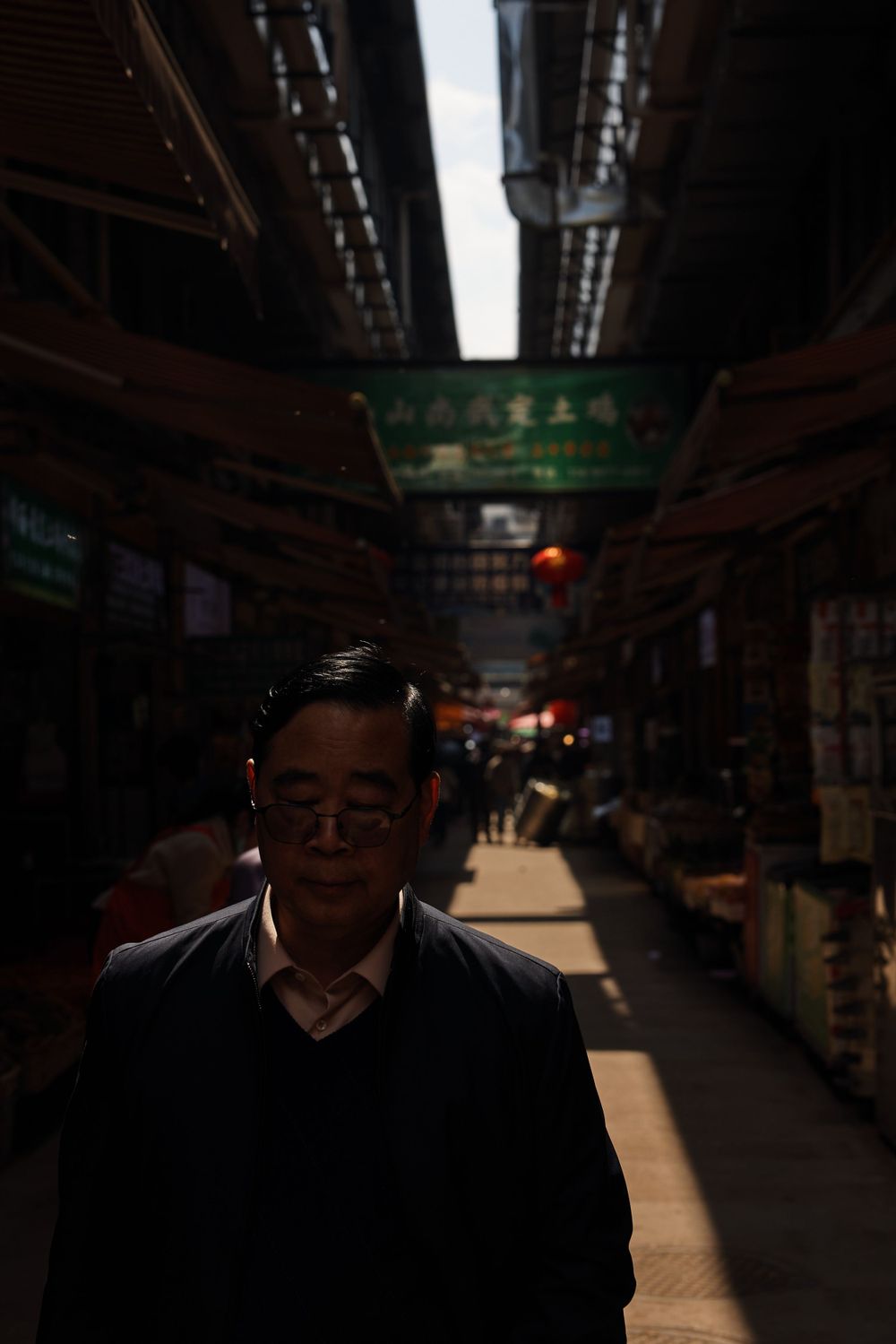 Dark indoor marketplace corridor with dramatic lighting and walkway leading into distance.