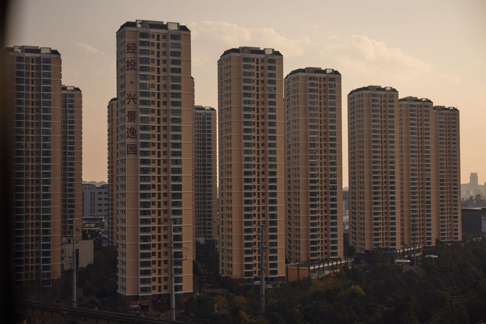 Row of tall identical residential high-rise apartment buildings at sunset creating an urban skyline silhouette.