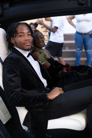 Young couple in formal wear seated in luxury vehicle with white leather interior.