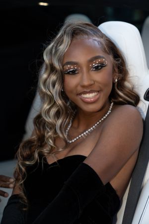 Glamorous evening makeup features sparkly eye details paired with a pearl necklace and black dress.