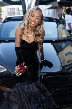 Glamorous formal wear in black velvet with mermaid silhouette and small red bouquet.