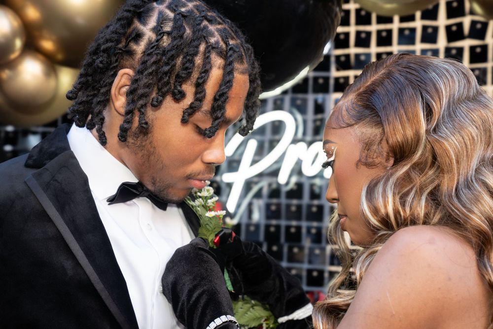 Formal couple shares intimate moment at prom with decorated backdrop.