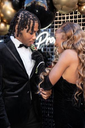 Candid moment between couple at formal event with balloon decorations and neon lighting.