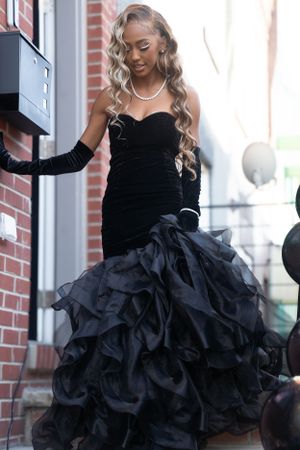 Dramatic black velvet and tulle prom dress with ruffled skirt photographed on brick steps.