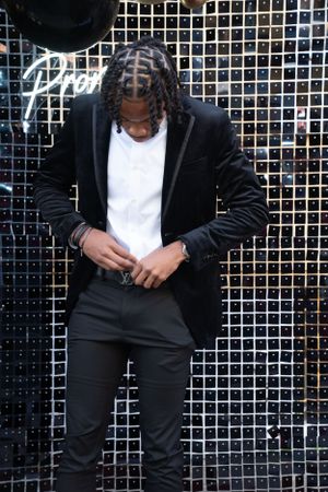 Fashion photo showing details of black tuxedo and belt against metallic backdrop.
