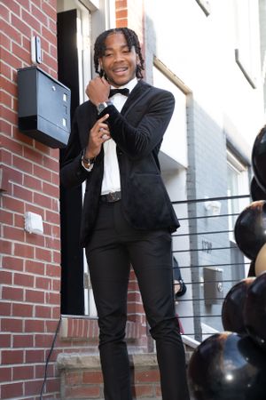 Elegant prom pose on brick steps with black balloons and formal attire.