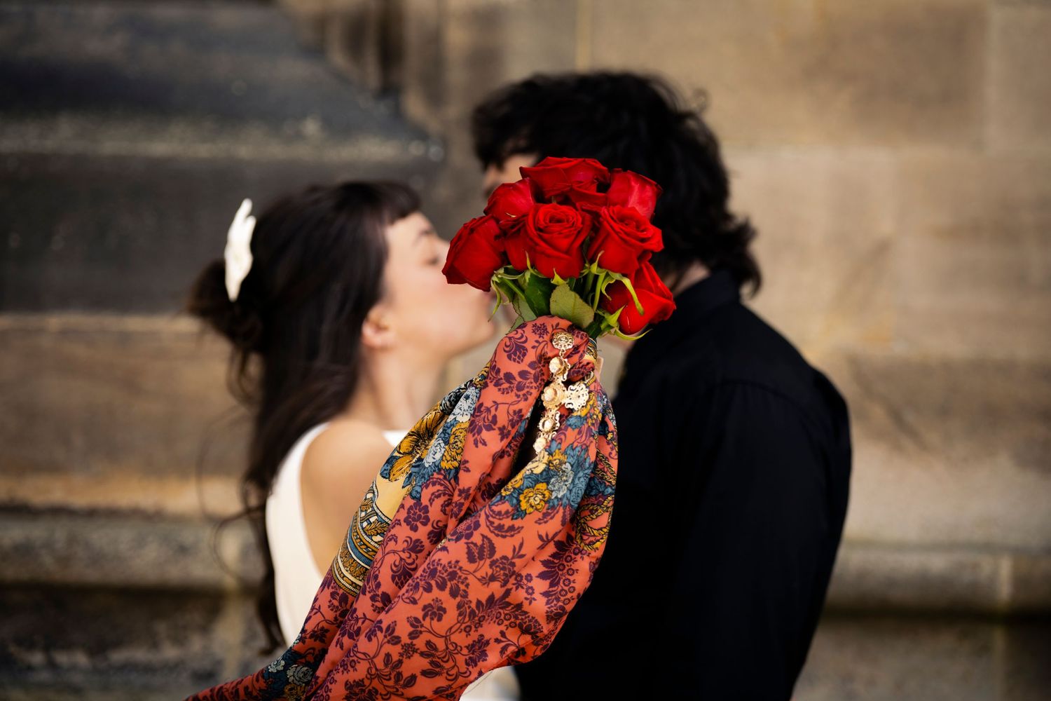Romantic close-up of a couple holding hands, with red roses and vintage fashion—capturing love, style, and heartfelt moments.