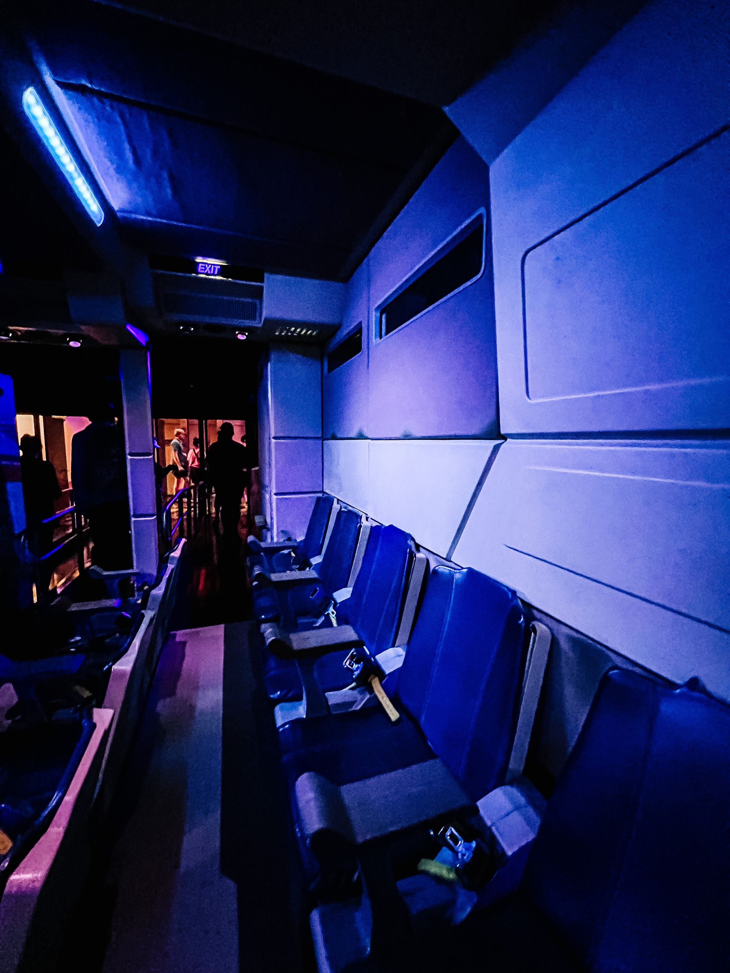 Low-lit corridor with angular geometric blue lighting creating an immersive sci-fi atmosphere in a modern venue space.