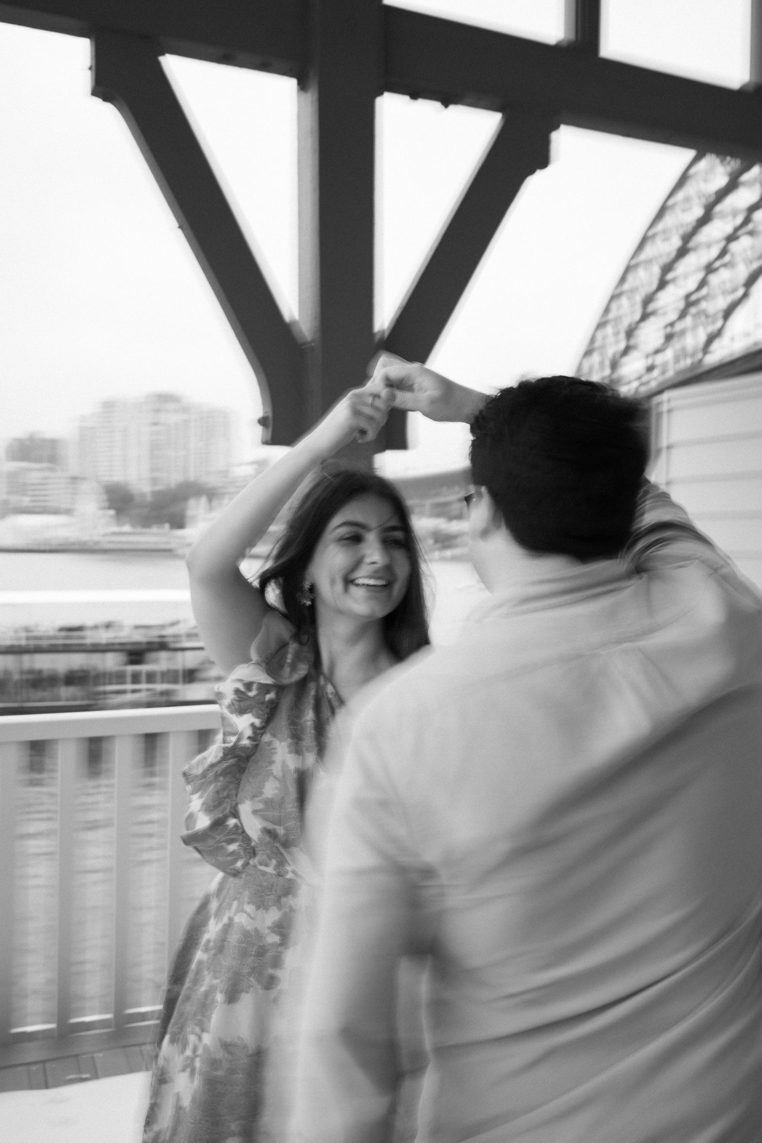 A couple dances together on a covered deck overlooking a city skyline.