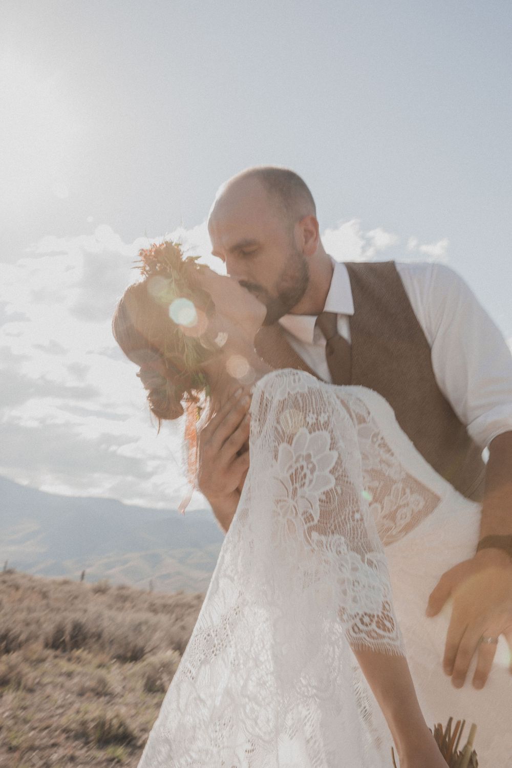Romantic couple sharing an intimate moment in a desert landscape with mountains and sunlight.