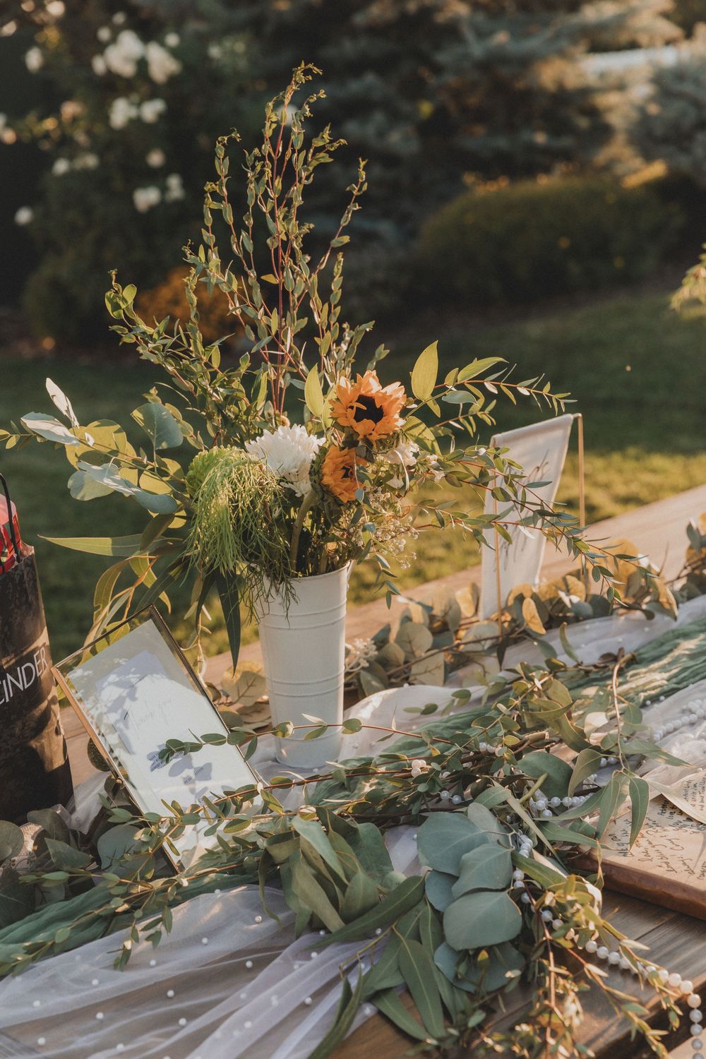 Rustic wedding table decorated with wildflowers, eucalyptus, and white table settings at sunset.