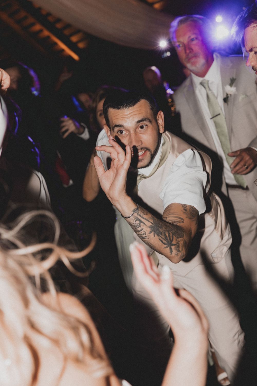 People dancing and celebrating at a nightclub with purple lighting and energetic atmosphere.