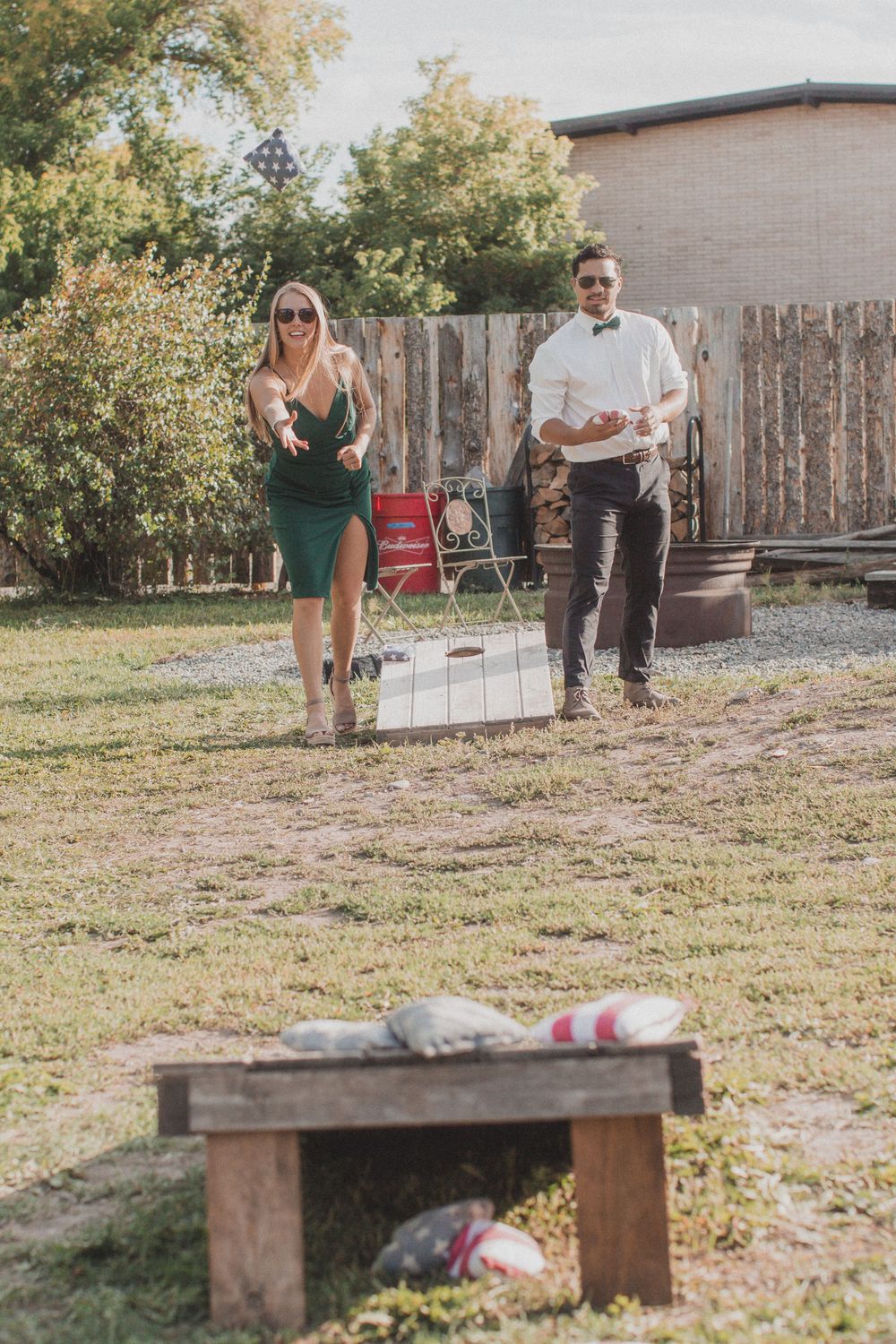 Outdoor wedding venue setup showing wooden benches on grass with trees in background.