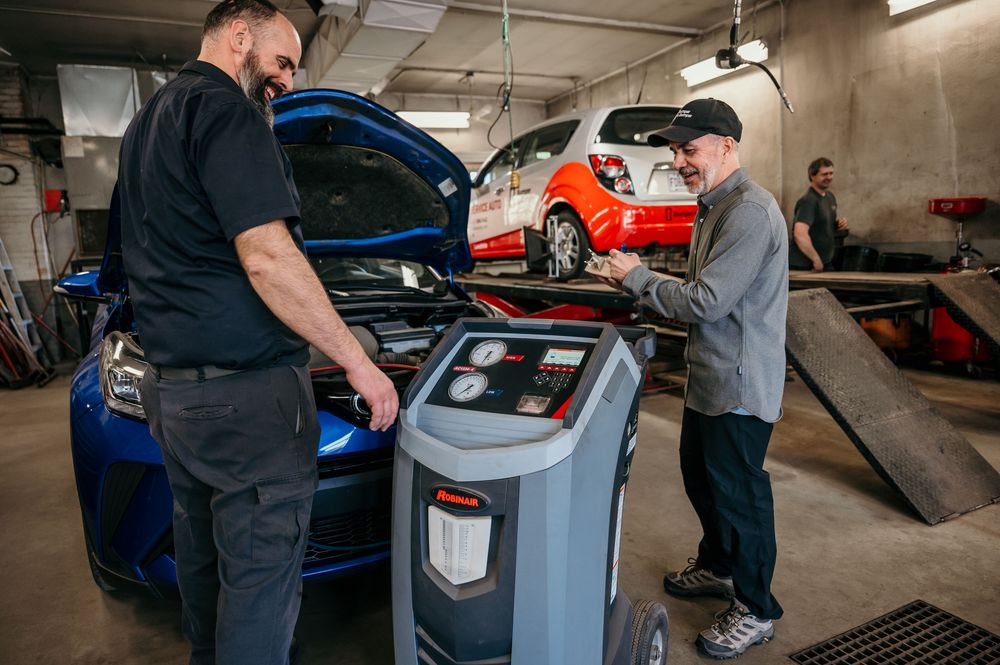 Automotive technicians using diagnostic equipment and tools to service vehicles in a professional repair garage.