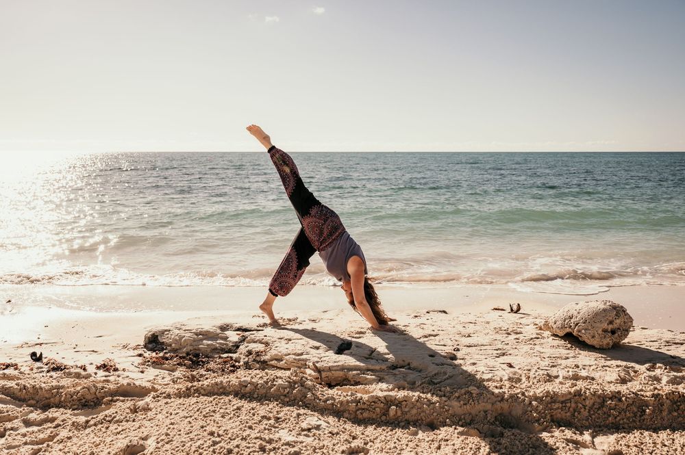 Sequence of someone doing a cartwheel on a sandy beach with ocean waves in the background.