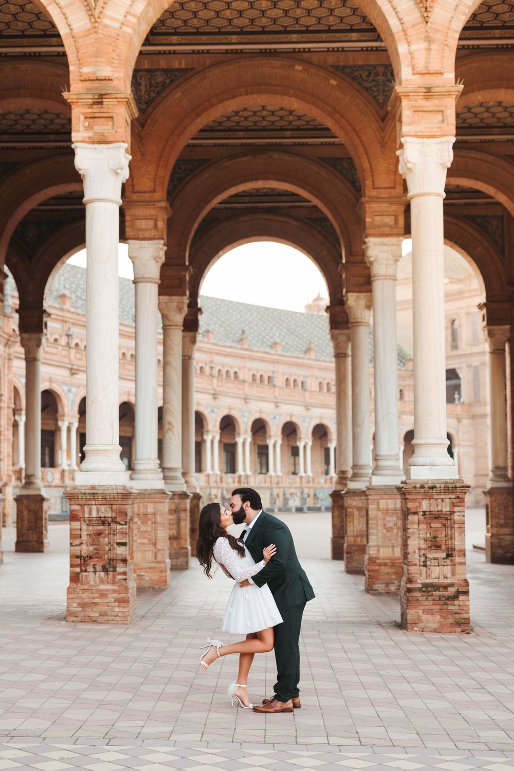 Romantic dance poses under the arched colonnade of Plaza de España.
