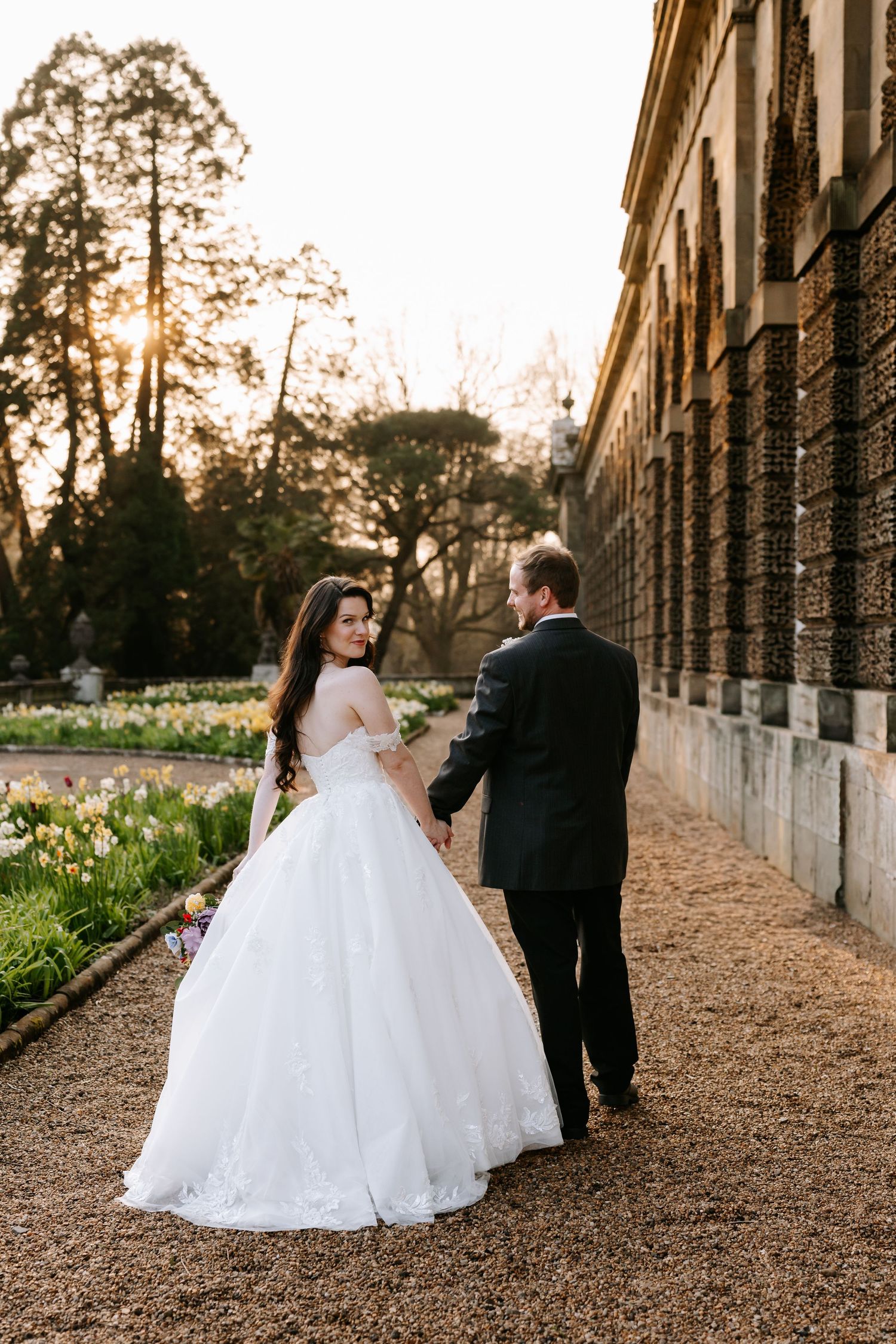 A bride and groom share a joyful moment together in a greenhouse setting filled with lush plants and natural light at the Orangery Margam