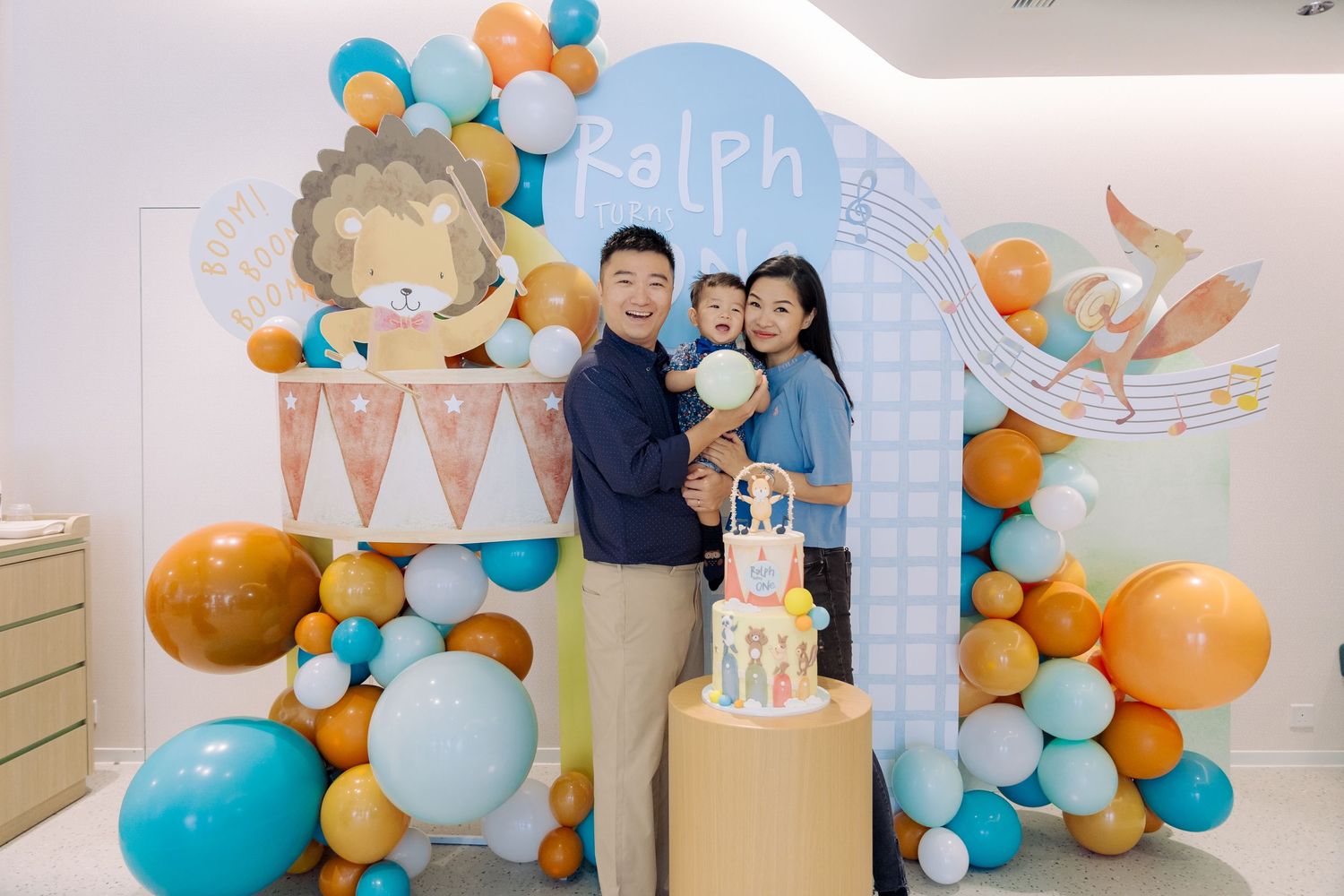 Balloon garland decorations in turquoise and gold create an elegant celebration backdrop at an indoor event space.