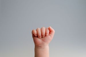 A series of seven baby hand photos showing different gestures and grasping positions against a light gray background.