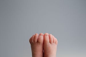 A close-up view of small baby feet against a plain gray background.