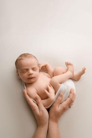 A newborn baby resting peacefully in gentle hands against a white background in multiple artistic angles.