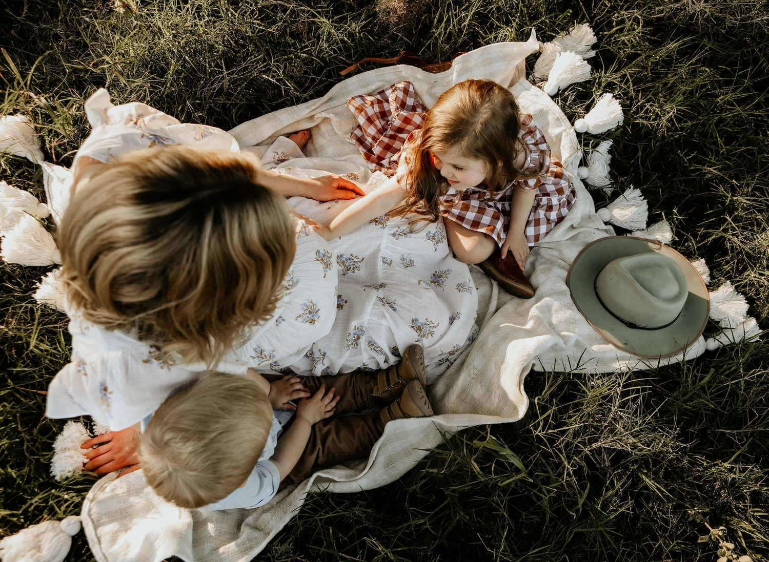 A couple lying on a white blanket in a grassy field, shown in a series of romantic candid moments.