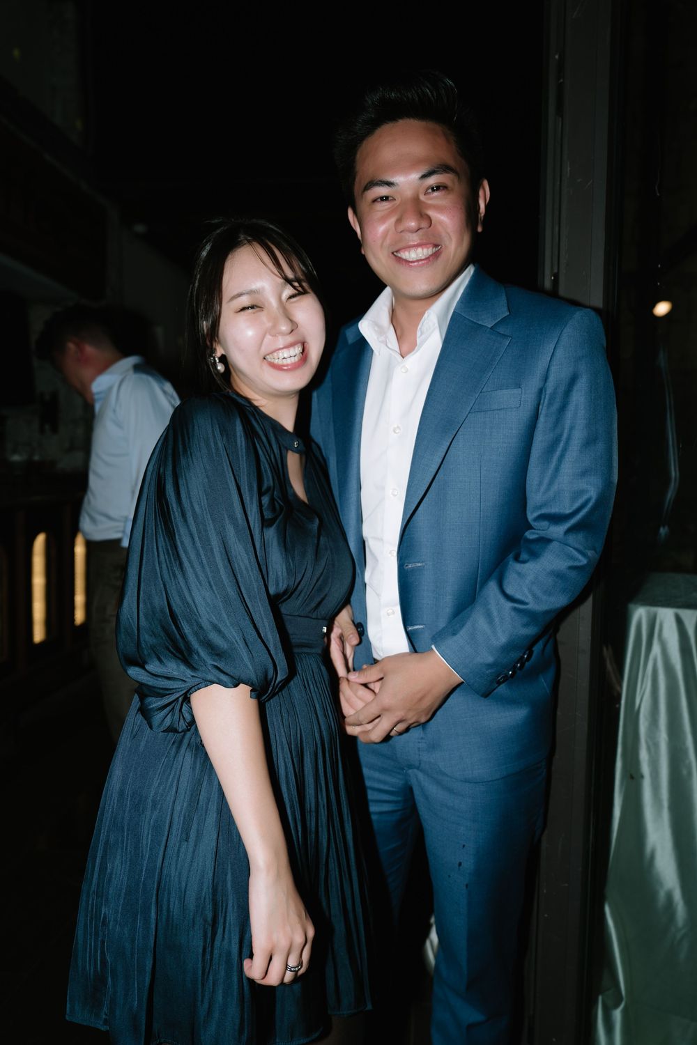 Smiling couple posing together at an elegant evening event, woman in blue dress and man in blue suit.