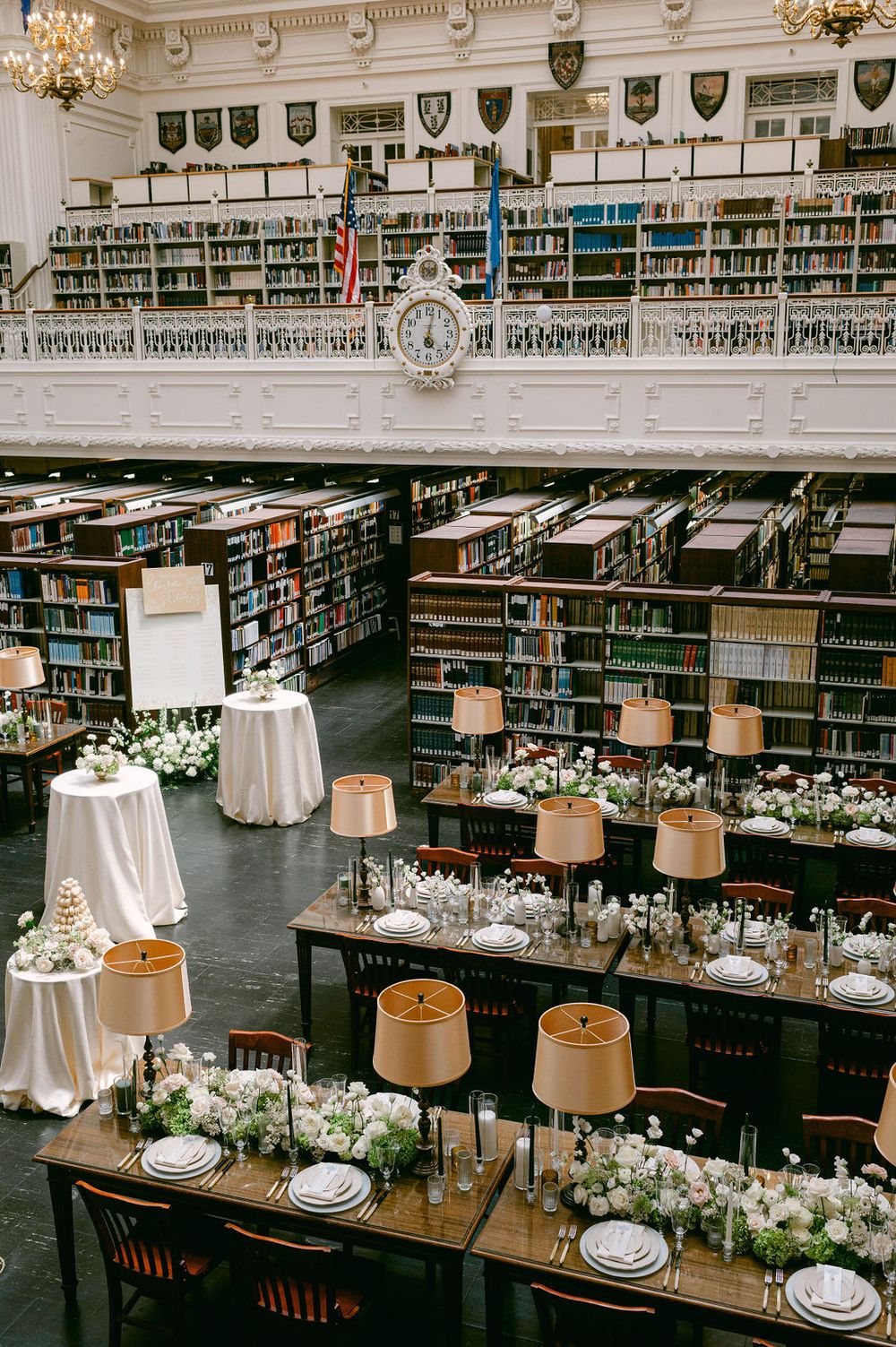 Library wedding reception setup with vintage wooden tables, white linens, and elegant place settings.