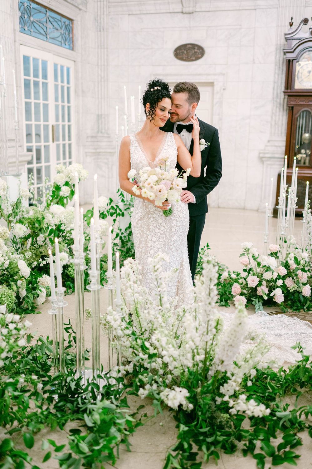 A romantic wedding scene with delicate white floral arrangements and greenery creating an elegant walkway.