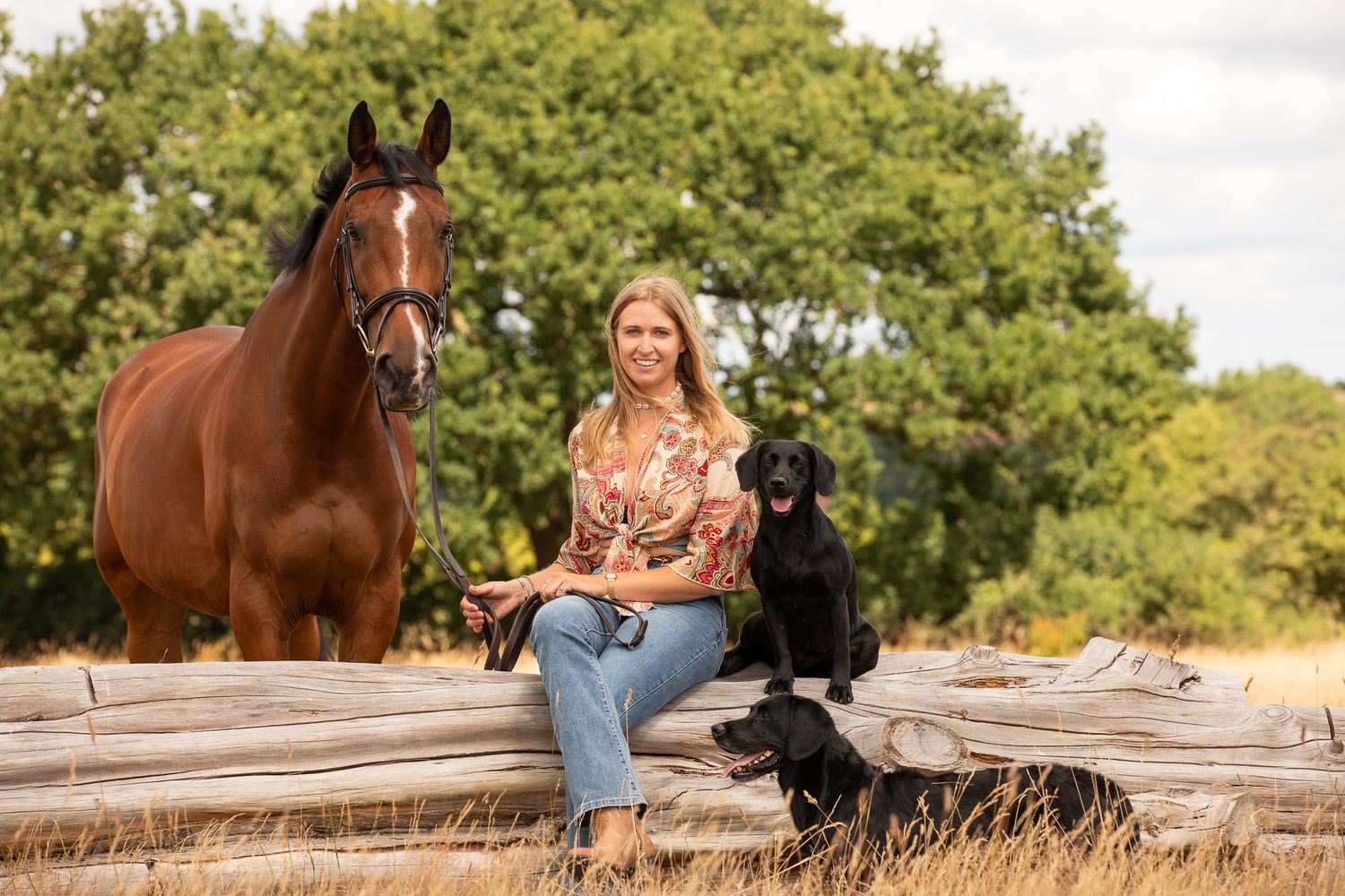 A horse and its rider enjoy an outdoor photoshoot session near rustic wooden fencing on a sunny day.