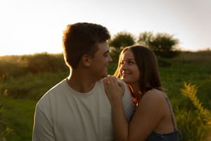 A couple shares a tender moment in golden hour lighting against a natural outdoor backdrop.