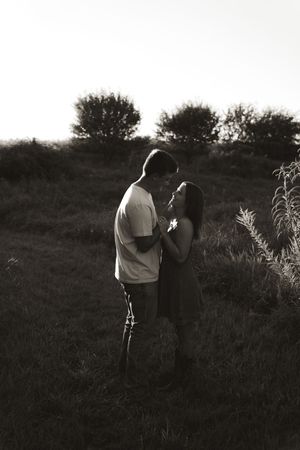A black and white portrait of a couple sharing an intimate moment in nature.