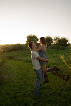Couple in casual attire sharing a playful moment in a grassy field.
