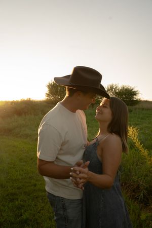 Couple in western attire sharing a romantic moment in golden evening light.
