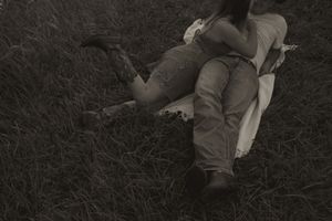 A couple rests together on a blanket in dark moody lighting.
