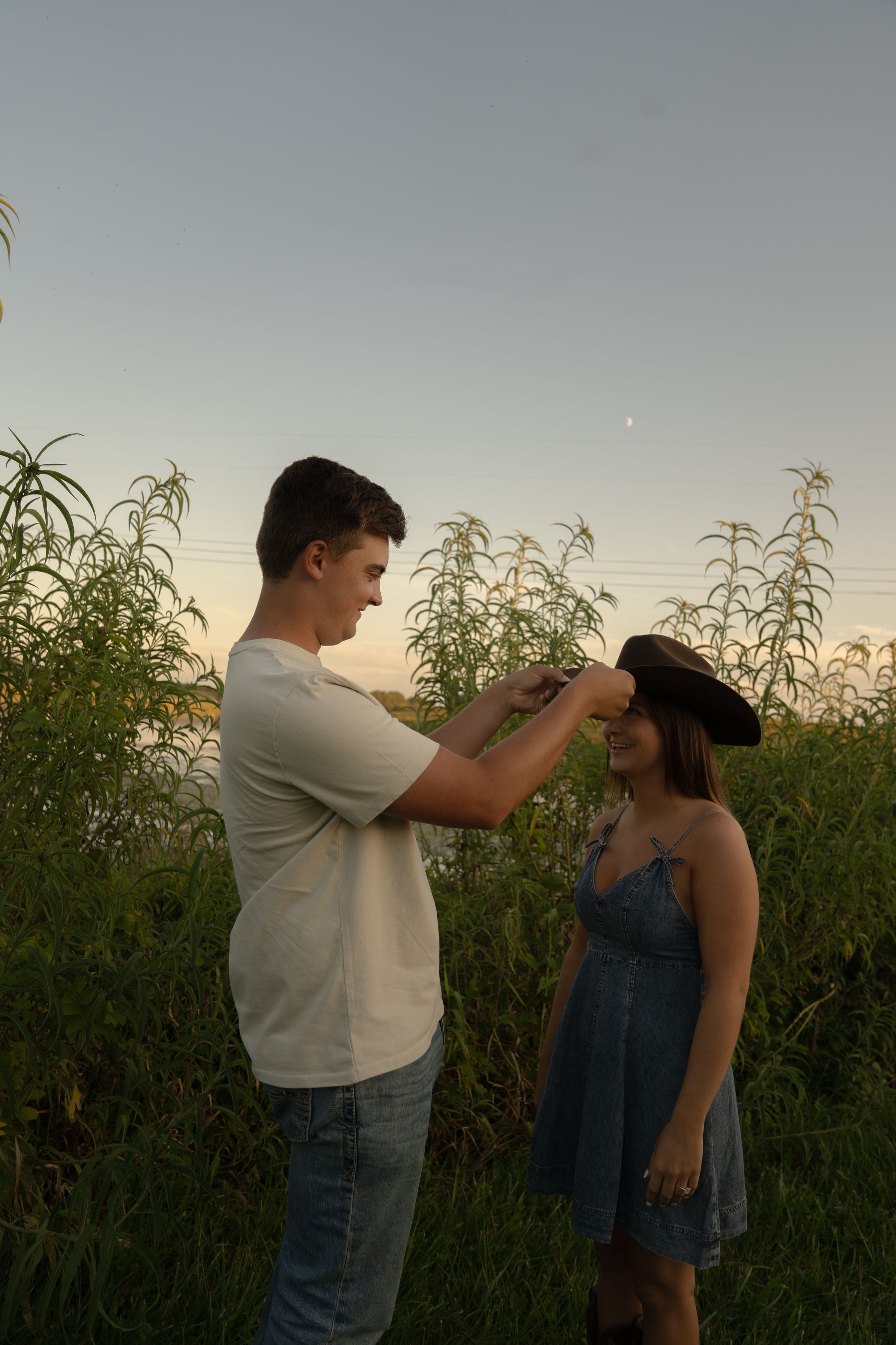 A sweet outdoor moment between two people in casual attire at dusk.