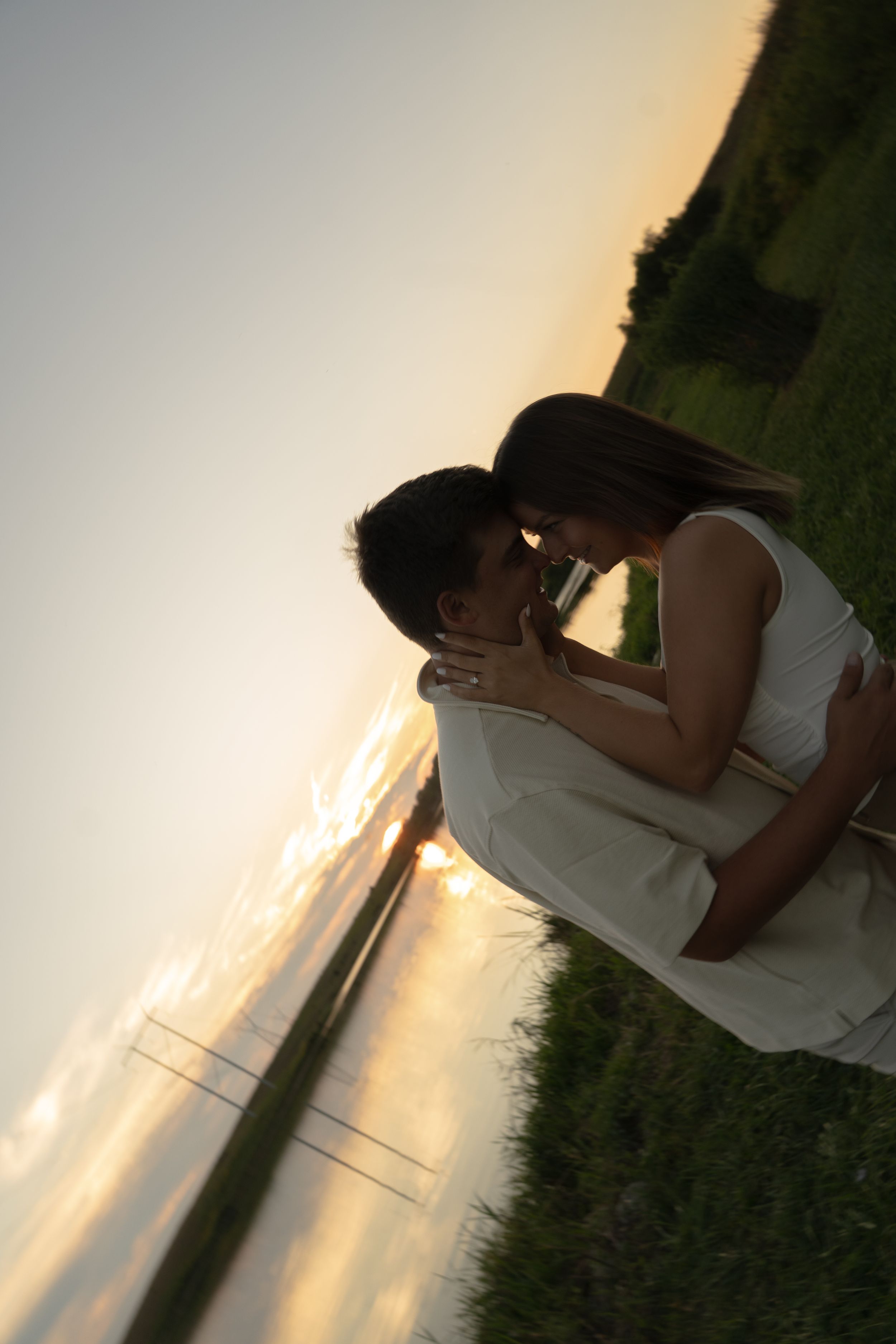 A silhouetted couple shares a tender moment against a warm sunset sky.