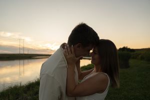 A romantic silhouette of two people against a sunset lake backdrop.